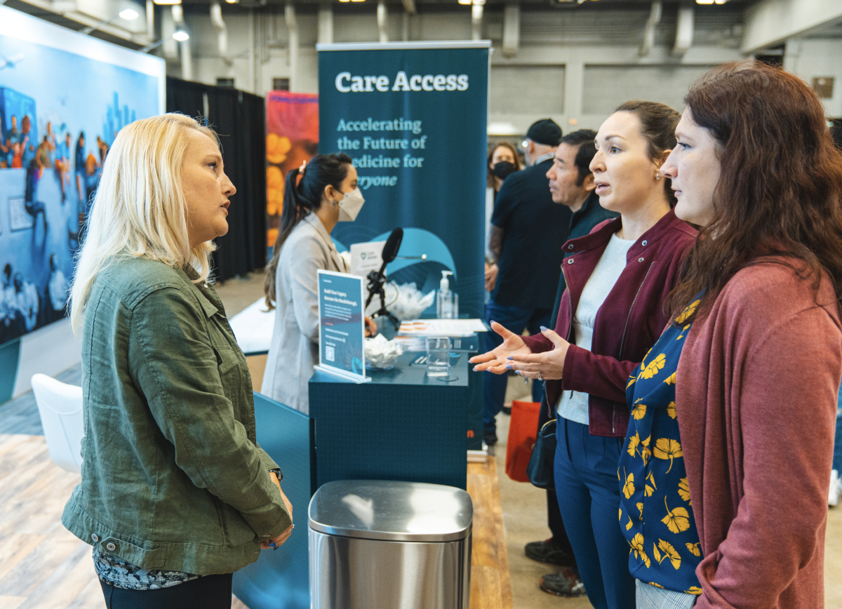 People talking at Care Access booth (SXSW 2023)