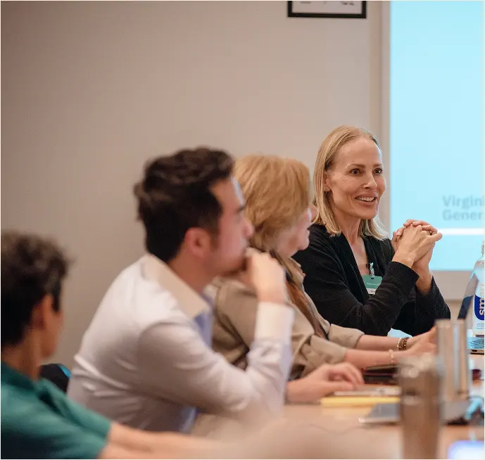 Woman speaking at a table with other people listening