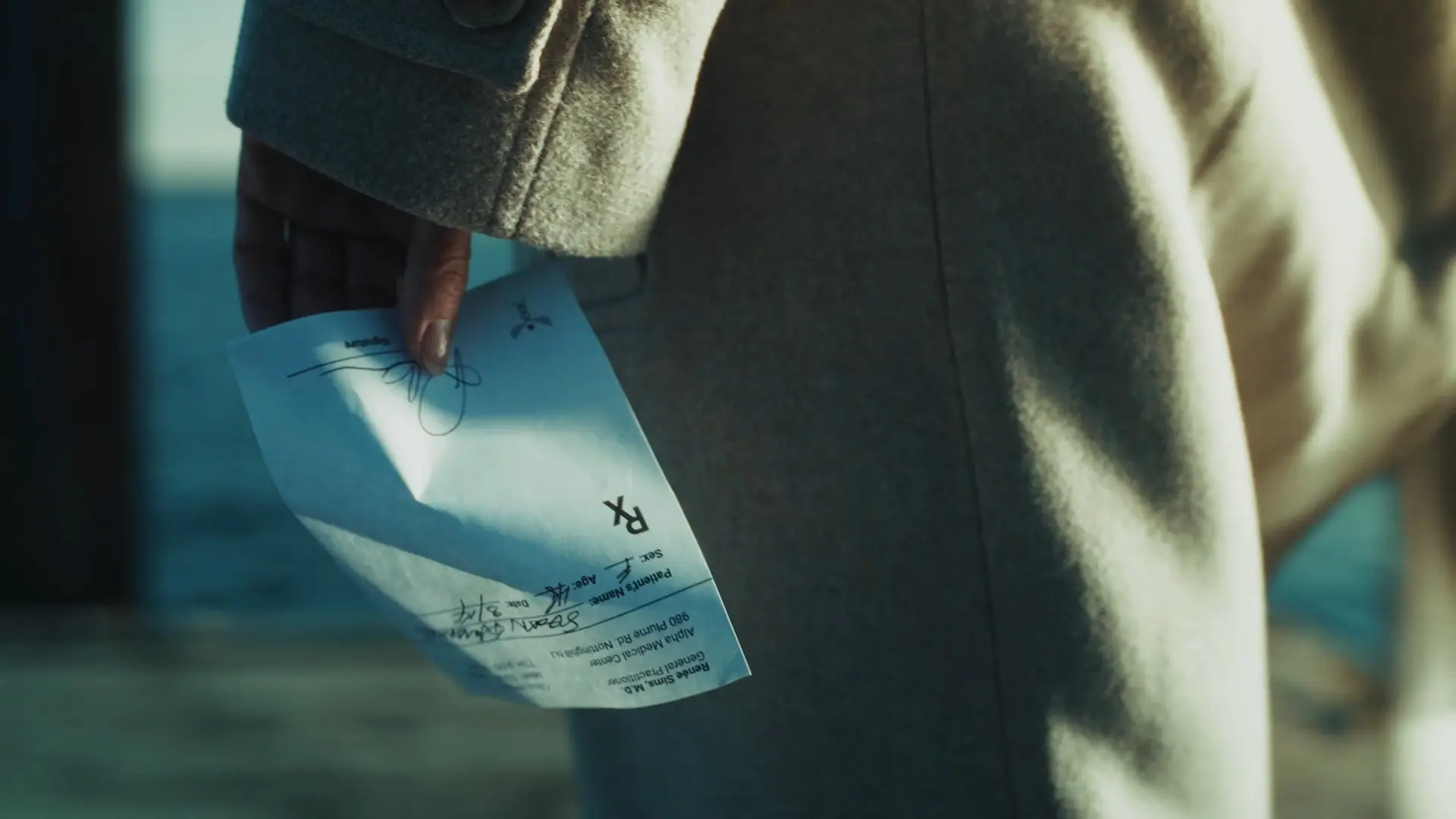 A hand holds a signed prescription slip with nothing written on it.