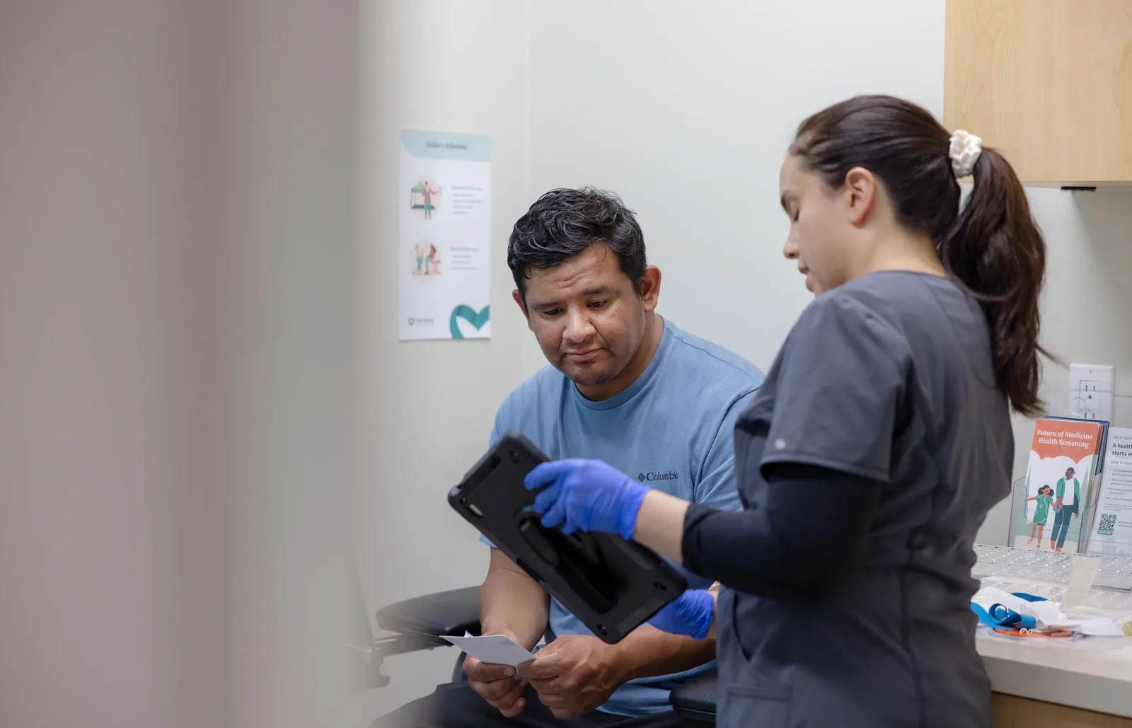A Care Access team member reviewing information on a tablet with a participant at a clinic desk