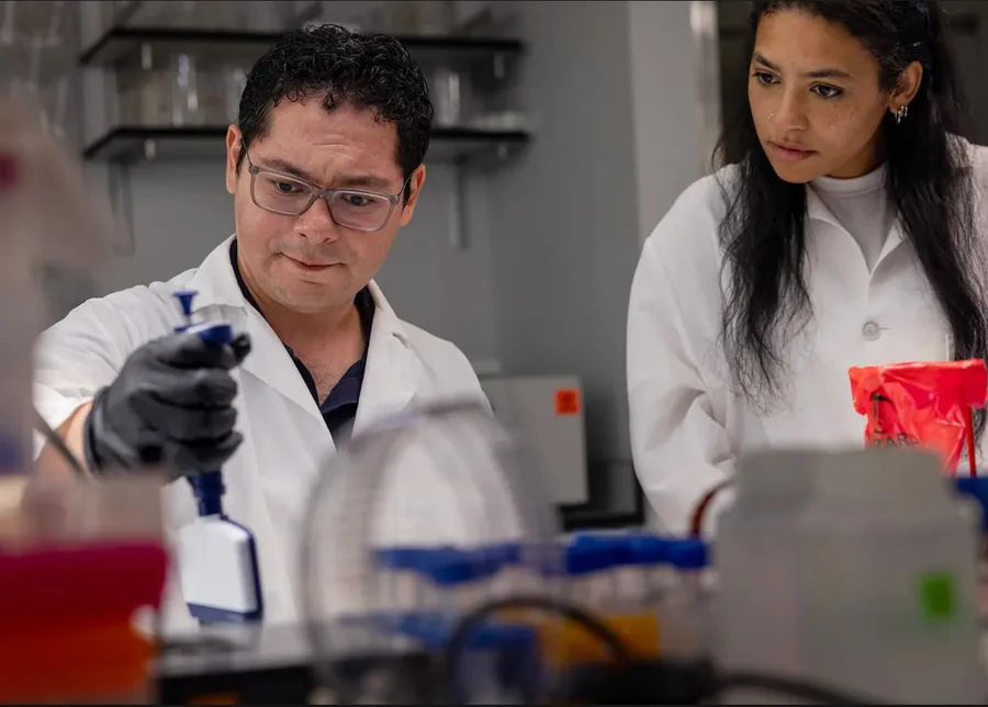 Two researchers in white coats working at a laboratory bench