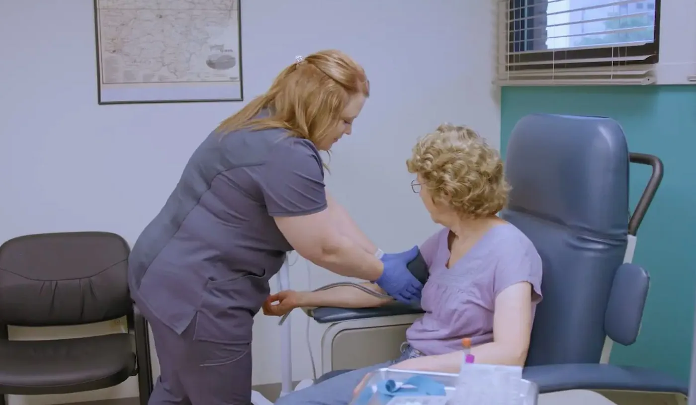 A Care Access nurse drawing blood from a seated participant