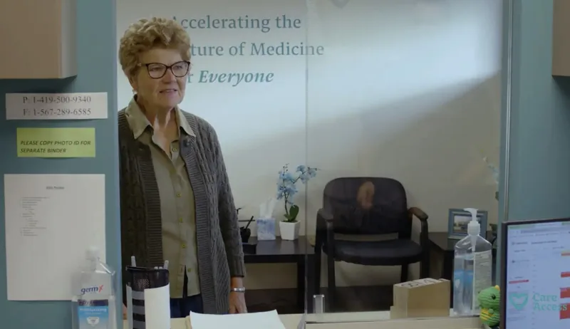 Joyce standing beside a Care Access wall graphic