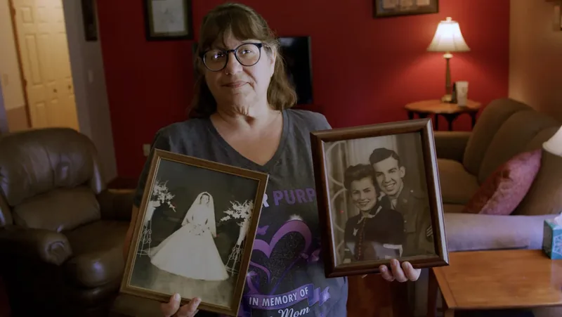 Lisa holding two framed family photographs